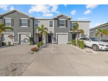 Two-story townhome with gray exterior, two-car garage, and landscaping at 8995 Milestone Dr, Sarasota, FL 34238