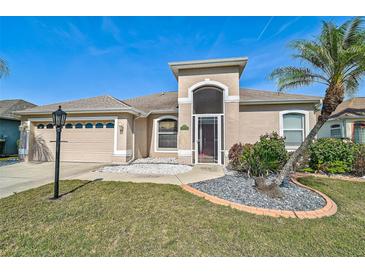 Charming single-story home with stucco siding, arched entryway, and well-maintained landscaping with mature palm trees at 10726 Old Grove Cir, Bradenton, FL 34212