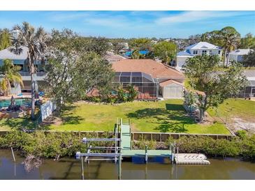 An aerial view of a home with a screened-in pool, green lawn, and dock on the water at 907 Garland Ave, Nokomis, FL 34275