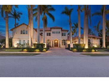 Elegant two-story home featuring lush landscaping, mature palm trees, and a beautiful paver driveway and walkway at 13315 Palmers Creek Ter, Lakewood Ranch, FL 34202