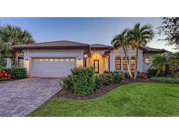 Charming home exterior with well-manicured landscaping, brick driveway, and a two-car garage at 14510 Leopard Creek Pl, Lakewood Ranch, FL 34202