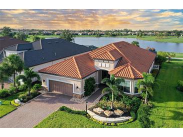 Beautiful waterfront home with a red tile roof, paver driveway, lush landscaping, and attached two-car garage at 15115 Montello Way, Lakewood Ranch, FL 34211