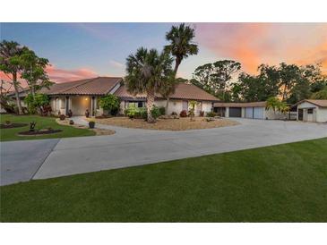 Lovely single-story home featuring a tile roof, mature landscaping, and an expansive driveway leading to a three-car garage at 265 Beaver Ct, Venice, FL 34292