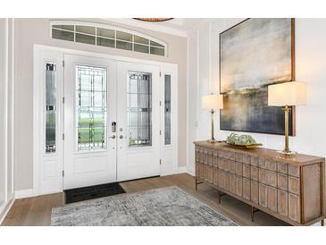 Elegant foyer features a glass-paneled front door, stylish console table, and modern artwork at 26891 Victoria Pl, Punta Gorda, FL 33955