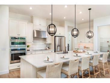 Bright kitchen featuring an island with seating, stainless steel appliances, and pendant lighting at 26908 Victoria Pl, Punta Gorda, FL 33955