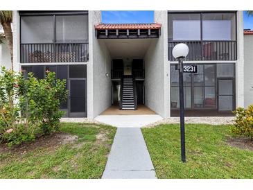 Inviting condo exterior with well-maintained lawn and direct access to upper and lower units, with beautiful plants and an address marker at 3231 Beneva Rd # 101, Sarasota, FL 34232