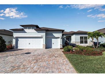 Charming home with a three-car garage, brick paved driveway, and professionally landscaped front yard at 8714 Backshore Ln, Parrish, FL 34219