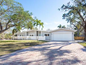 Charming single Gathering home with a brick driveway, luscious mature trees and an attached two car garage at 1240 Northport Dr, Sarasota, FL 34242