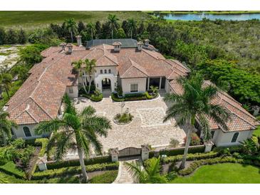 Expansive estate featuring a grand circular driveway, lush landscaping, and a serene lake view at 16416 Baycross Dr, Lakewood Ranch, FL 34202