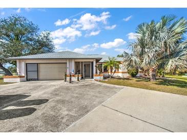 Charming single-story home featuring an attached garage, screened entryway, and mature landscaping at 19484 Midway Blvd, Port Charlotte, FL 33948