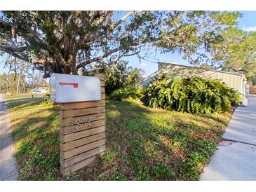 Charming home exterior featuring a decorative mailbox, lush greenery, and mature trees, creating a welcoming curb appeal at 2375 Riverwood Pines Dr, Sarasota, FL 34231