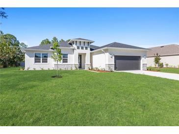 Inviting single-story home with a well-manicured lawn, a two-car garage, and modern architectural accents at 2388 Armenia Rd, North Port, FL 34286