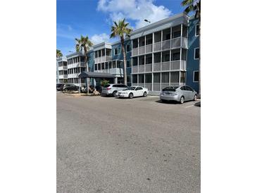 Exterior view of building with parking lot and tropical landscaping on a sunny day at 2755 Coconut Bay Ln 1K # 119, Sarasota, FL 34237