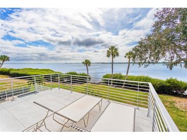 Relaxing balcony with white railing overlooking water and clear blue sky with two lounge chairs facing scenic waterfront views at 55 Tidy Island Blvd, Bradenton, FL 34210