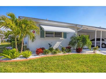 Charming home featuring beautifully landscaped front yard with palm trees and pristine green lawn at 6016 Hibiscus Dr, Bradenton, FL 34207