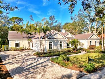 Elegant home showcasing a circular paver driveway, lush landscaping, and a three-car garage at 67 Sugar Mill Dr, Osprey, FL 34229