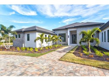 Stunning single-story home featuring a stone facade, well-manicured landscaping, and a brick paver walkway at 8487 Lindrick Ln, Bradenton, FL 34202