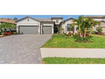 Beautiful home exterior with a well-manicured lawn, palm trees, and a three-car garage at 15607 White Linen Dr, Lakewood Ranch, FL 34211