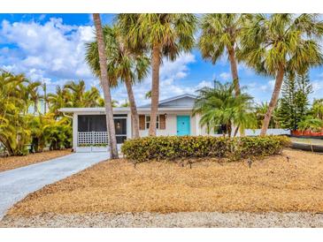 Charming single-story home with a vibrant blue door and well-maintained landscaping at 310 Magnolia Ave, Anna Maria, FL 34216