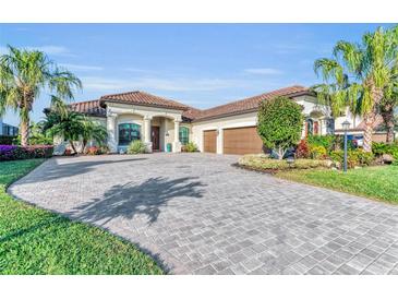Stunning home featuring a brick driveway, lush landscaping, and a tile roof at 5529 Mulligan Way, Bradenton, FL 34211
