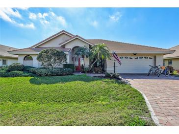 Charming single-story home featuring lush landscaping and a brick driveway leading to an attached two-car garage at 104 Inlets Blvd # 104, Nokomis, FL 34275