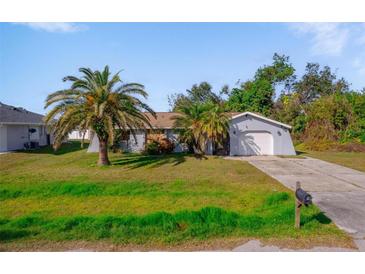 Charming single-story home features a well-maintained front yard with mature palm trees and a private driveway at 1124 Ample Ave, Port Charlotte, FL 33948