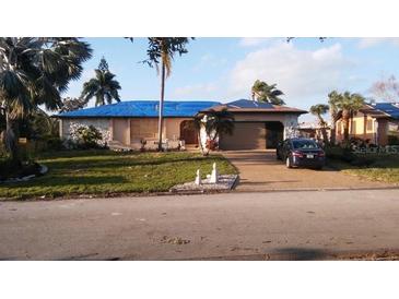 Exterior view of the house with a blue roof tarp and debris scattered around the yard at 1627 Baywinds Ln, Sarasota, FL 34231