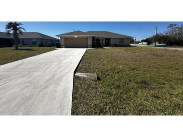 Charming single-story home with a well-manicured lawn and a concrete driveway leading to an attached garage at 2001 Logsdon St, North Port, FL 34287