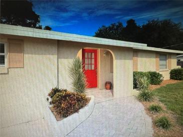 Charming home featuring an arched doorway with a vibrant red door and well-maintained landscaping at 3060 Arrowhead Rd, Venice, FL 34293