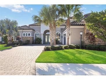 Beautiful home with a well-manicured lawn, palm trees, and a brick driveway at 4744 Benito Ct, Lakewood Ranch, FL 34211