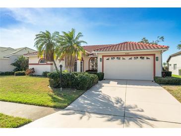 Charming single-story home showcasing a red tile roof, palm trees, and a well-maintained front yard at 5080 Kilty E Ct, Bradenton, FL 34203