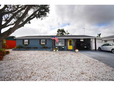 Charming single-story home with a yellow front door, stone landscaping, and a covered carport at 5419 1St W Ave, Bradenton, FL 34209