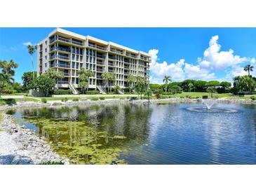 Beautiful exterior of condo building with serene pond view and lush tropical landscaping at 1105 Gulf Of Mexico Dr # 603, Longboat Key, FL 34228