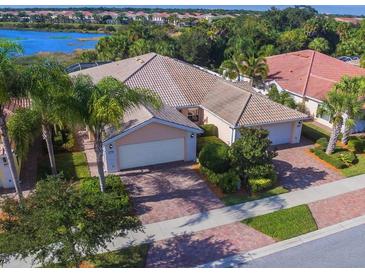 Beautiful home with tile roof, mature landscaping, paver driveway, and gorgeous lake view at 11629 Garessio Ln, Sarasota, FL 34238