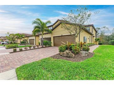 Charming two-story villa with lush landscaping, a brick driveway, and a two-car garage at 12510 Ghiberti Cir # 102, Venice, FL 34293