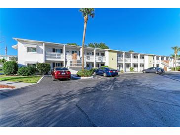 Condominium exterior featuring well-maintained landscaping and ample parking space under clear, blue skies at 1517 Pleasant Rd # A22, Bradenton, FL 34207