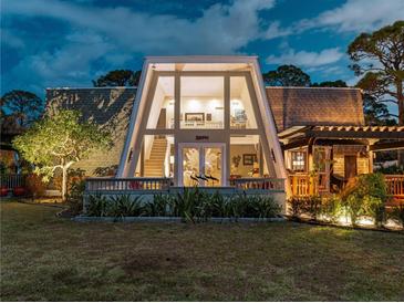 Stunning home featuring A-frame windows, a charming front porch, and lush landscaping at 1627 Bayshore Dr, Englewood, FL 34223