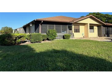 Well-kept single story home has a light yellow exterior, screen enclosed lanai and a manicured front lawn at 4197 66Th Street W Cir, Bradenton, FL 34209