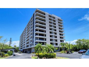 Multi-story condo building shows tropical landscaping and a parking area on a clear, sunny day at 6415 Midnight Pass Rd # 508, Sarasota, FL 34242