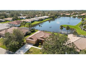 Beautiful aerial view of a home with a red tile roof, nestled next to a serene lake and lush greenery at 6637 Deering Cir, Sarasota, FL 34240