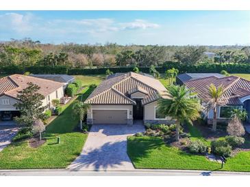 Beautiful single-story home with tile roof, paver driveway, lush landscaping, and two-car garage at 7140 Marsh View Ter, Bradenton, FL 34212