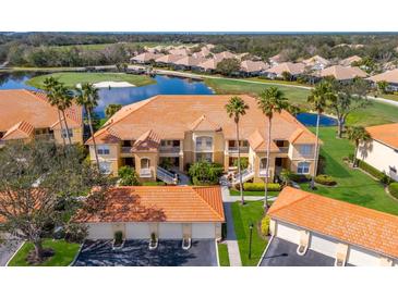 Beautiful building with tile roof situated alongside a golf course, pond and lush tropical landscape at 8414 Wethersfield Run # 102, Lakewood Ranch, FL 34202