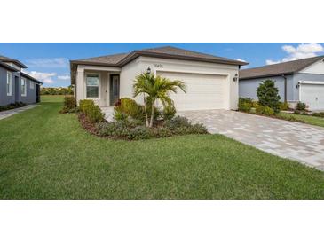 Charming home featuring a well-manicured lawn, an attached garage, and decorative landscaping at 10470 Spring Tide Way, Parrish, FL 34219
