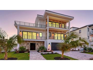 Contemporary three-story home featuring balconies, stone accents, and a well-manicured lawn at 1210 Gulf Blvd, Englewood, FL 34223