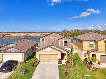 Beautiful two-story home with a well-manicured lawn, lush landscaping, and a vibrant red front door at 13528 Sunset Sapphire Ct, Parrish, FL 34219