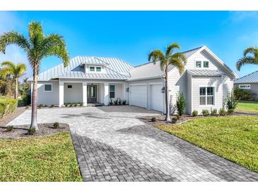 Stunning single-story home boasts lush landscaping, a brick driveway, and a stylish metal roof at 28960 Gin Ln, Punta Gorda, FL 33982