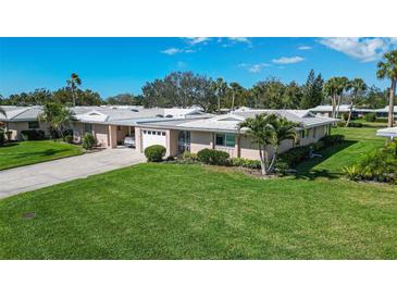 Charming single-story home featuring an attached garage, mature landscaping, and a well-manicured lawn at 3278 Village Green Dr # 1024, Sarasota, FL 34239