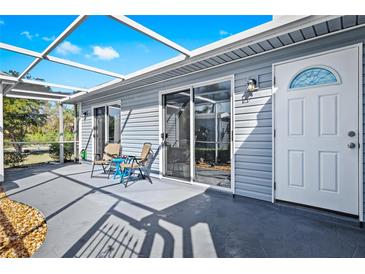 A covered patio with a table and chairs leads to a sliding glass door and a white door with an arched window at 3300 Loveland Blvd # 3203, Punta Gorda, FL 33980