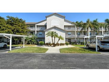 Well-maintained condo building featuring lush landscaping, covered parking, and sidewalks at 8755 Olde Hickory Ave # 7204, Sarasota, FL 34238