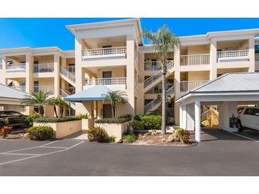 Attractive multi-story condominium with white railings, beige walls, and mature palm trees at 2424 Placida Rd # C104, Englewood, FL 34224